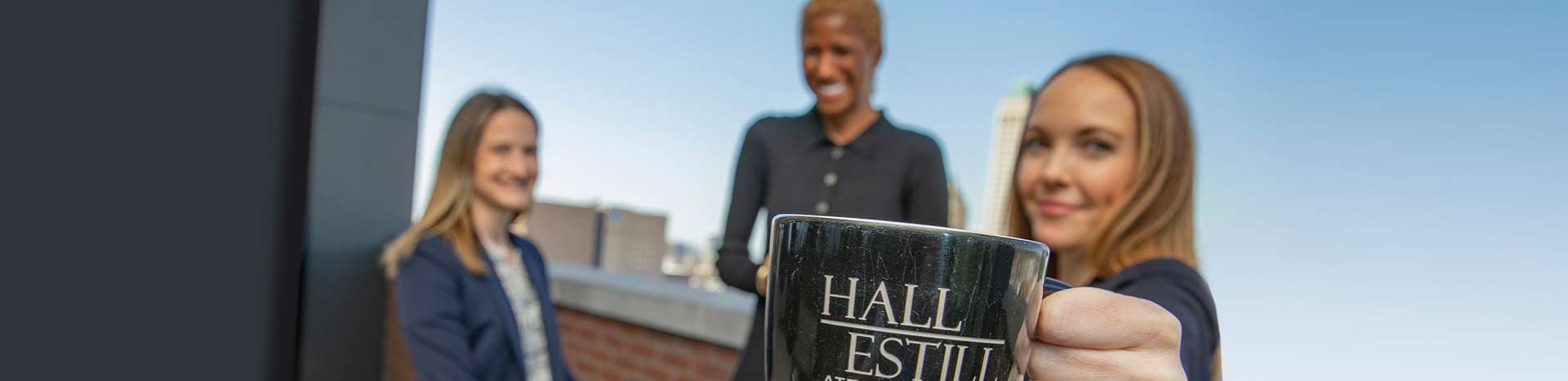 Attorneys Smiling While Holding Hall Estill Attorneys at Law Coffee Mug